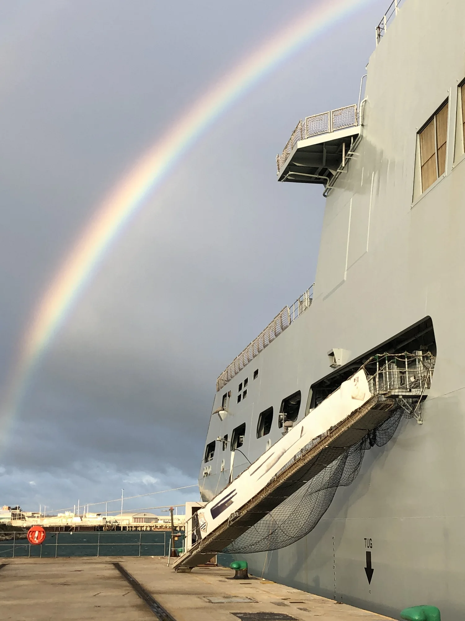 Large support vessel alongside beneath a rainbow
